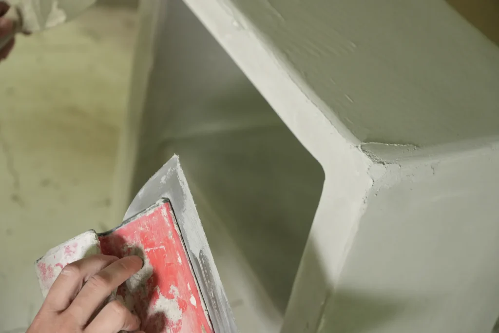 Artisane qui lisse l’arête d’un meuble en béton ciré