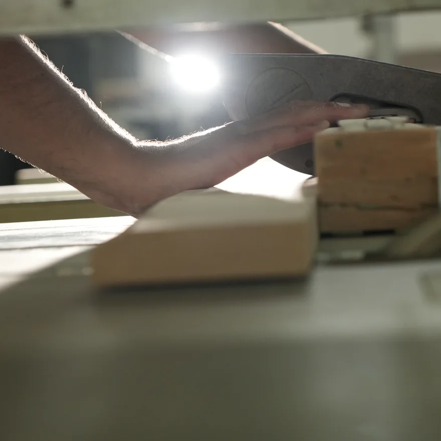 Main guidant un bloc de bois contre une lame de scie