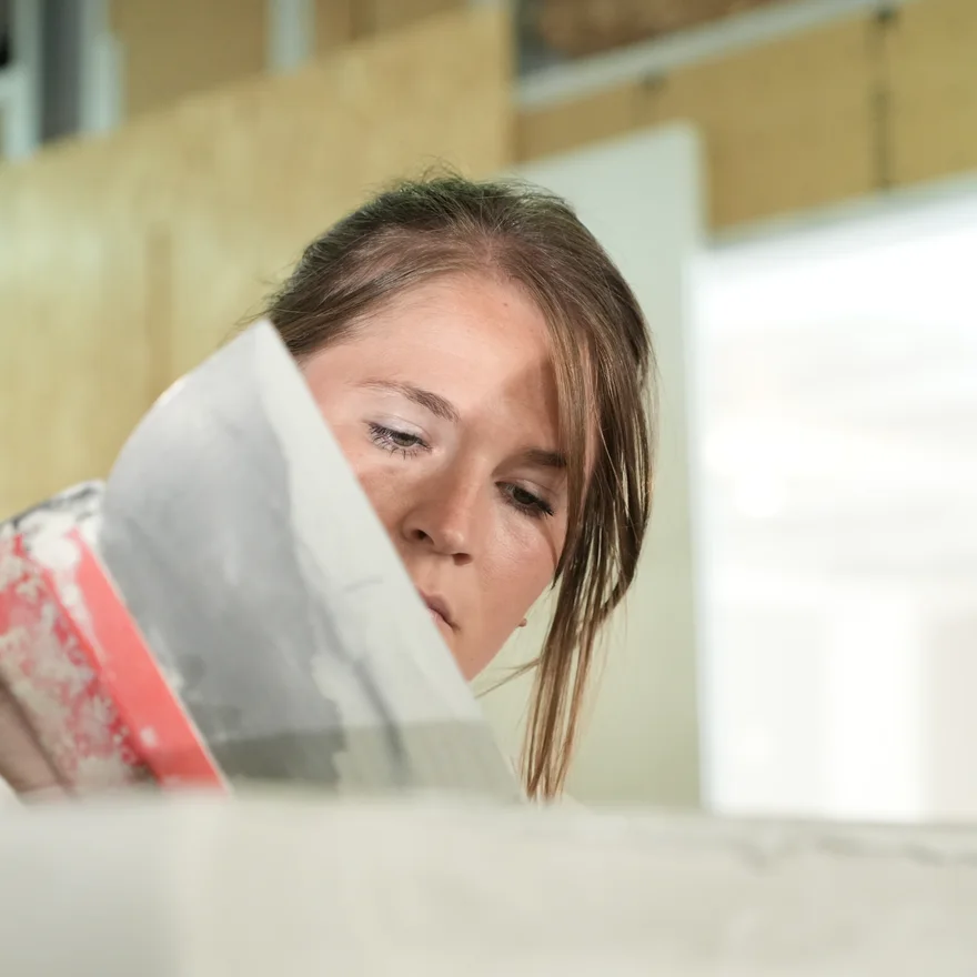 Artisane appliquant du béton ciré à la spatule dans l’atelier