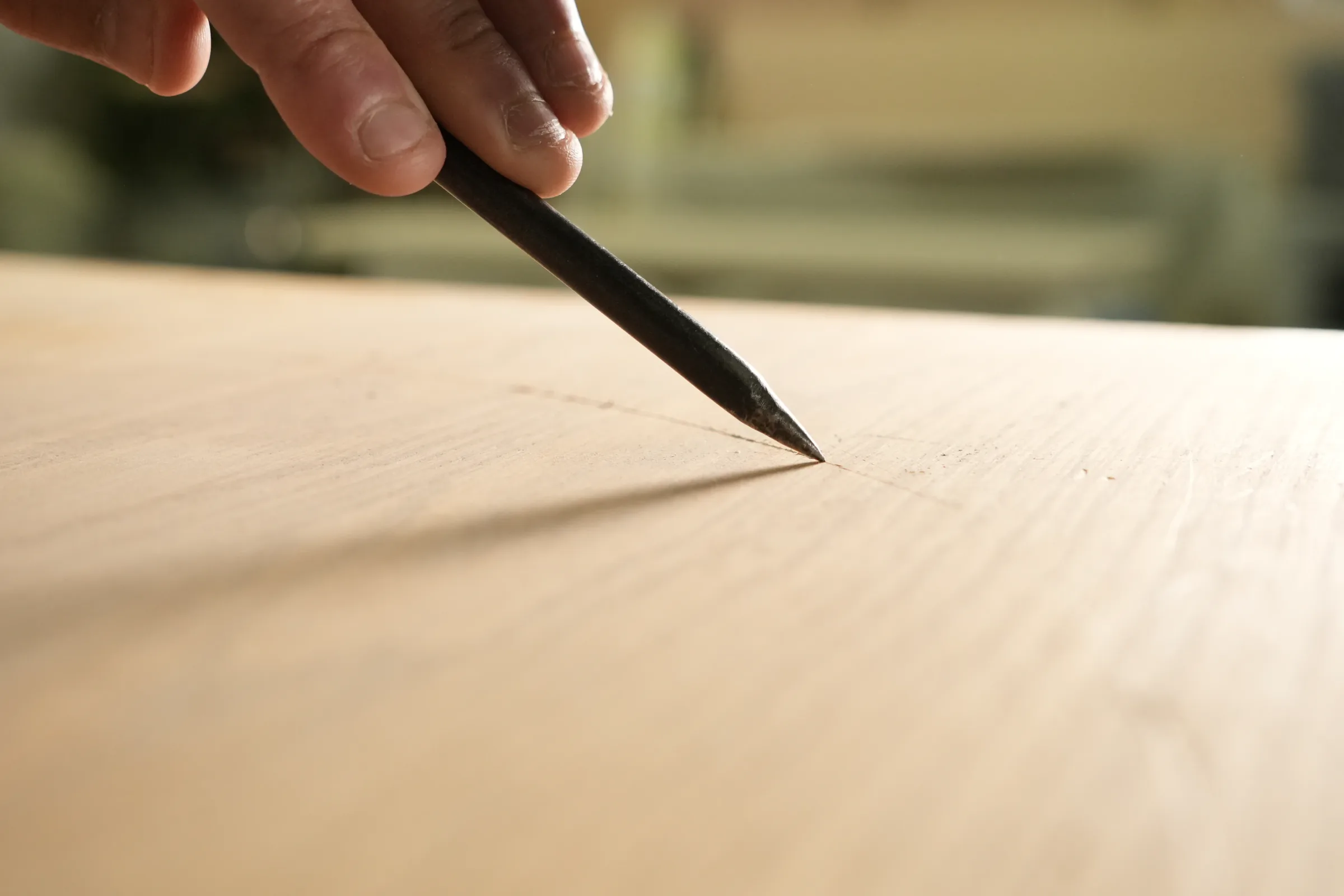 Main d’artisan traçant un dessin au crayon sur du chêne