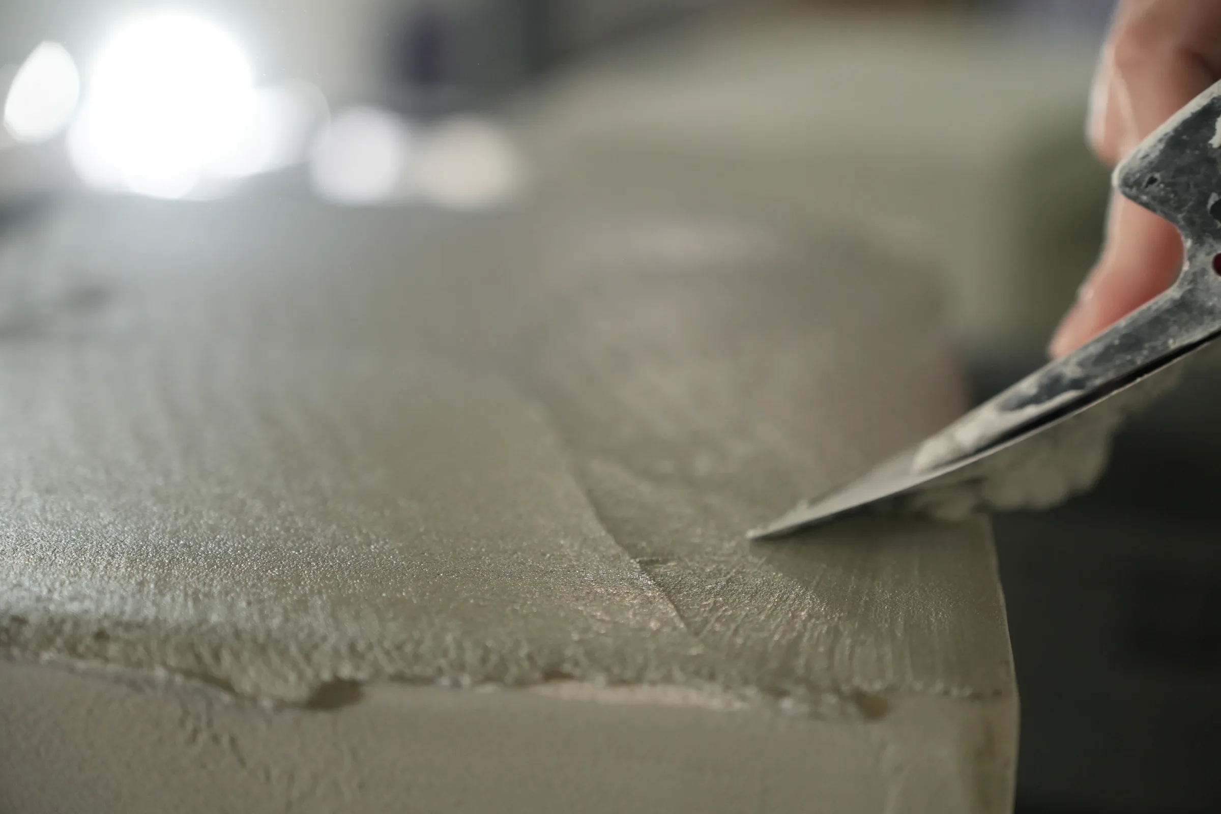 Spatule qui lisse l’arête d’un meuble en béton ciré